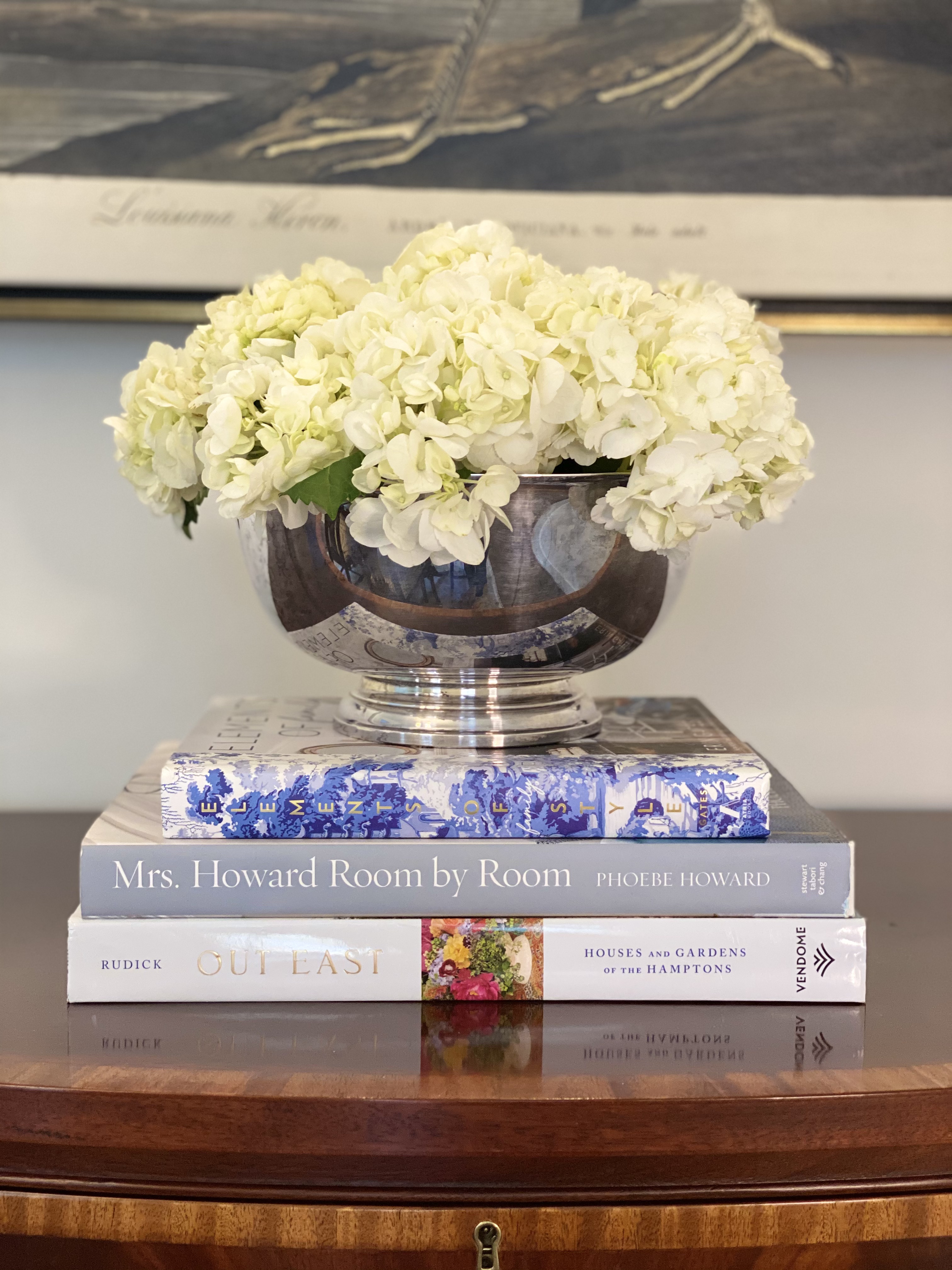 Hydrangeas in a silver bowl atop a stack of design books