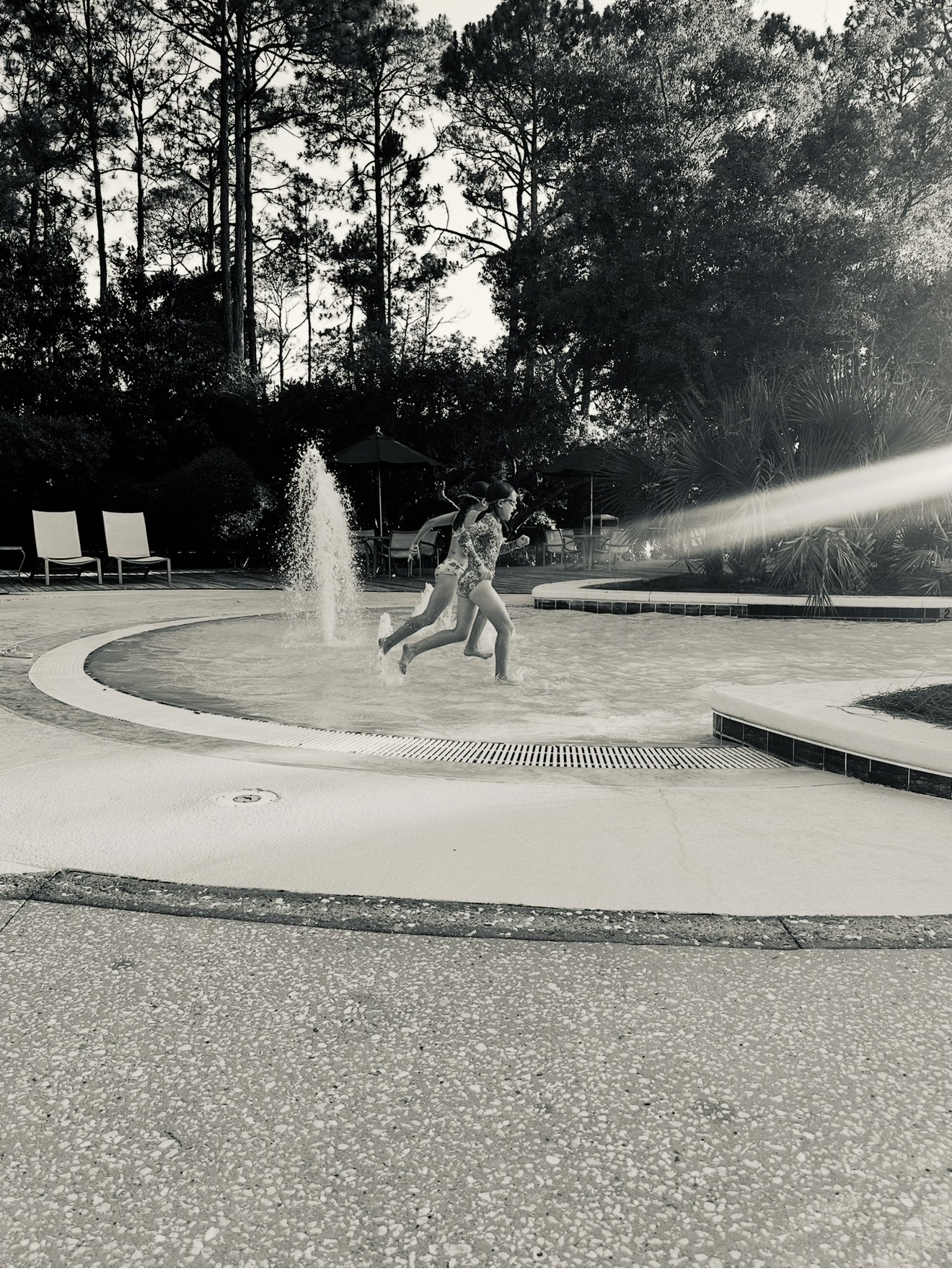 Girls running through the pool fountain